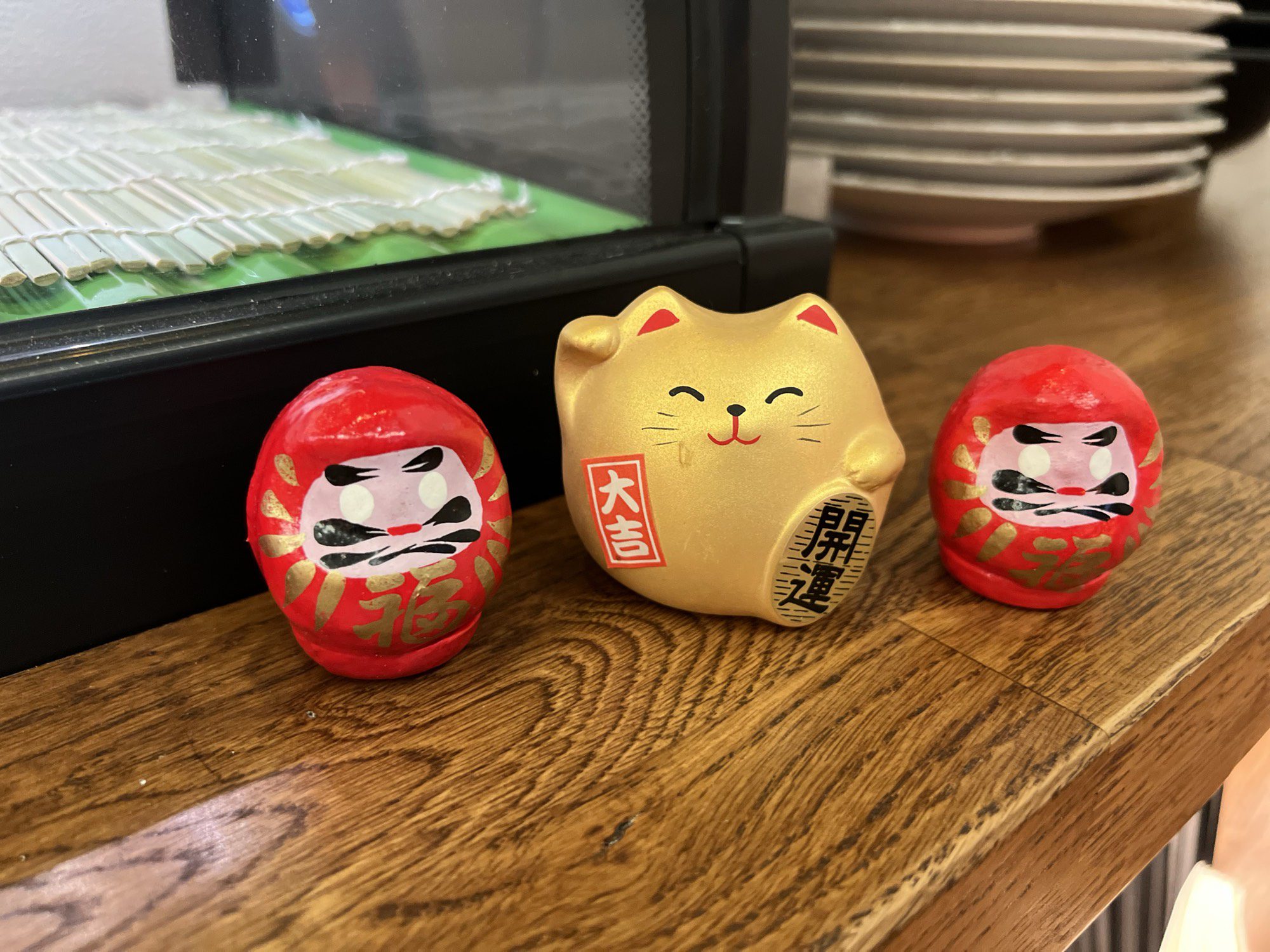 Daruma-Figuren und Glückskatze auf der Theke