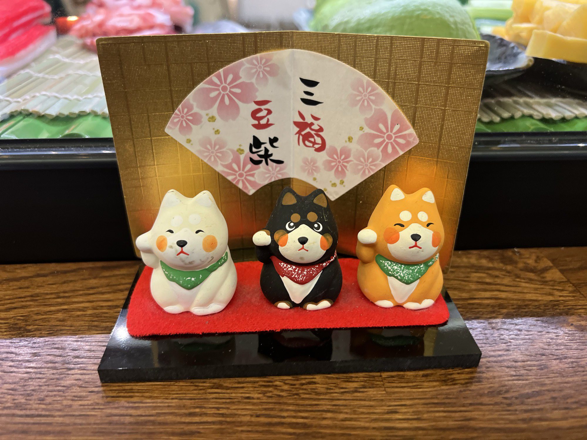 Drei Shiba-Figuren auf einem roten Podest